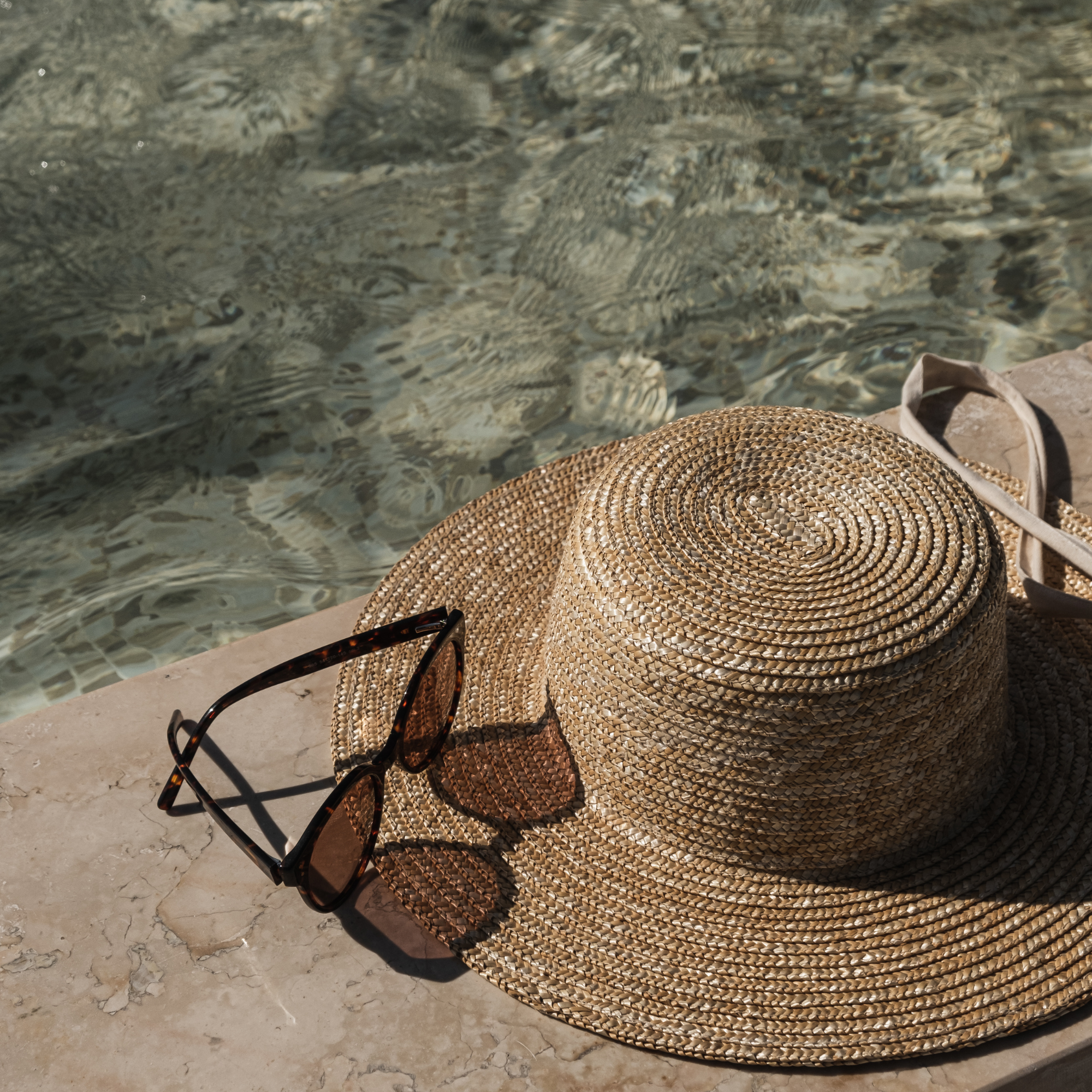 straw hat and glasses at side of pool