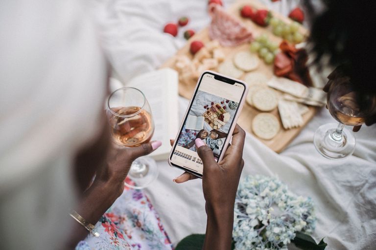 Overhead view of a picnic scene with people capturing moments using a smartphone.